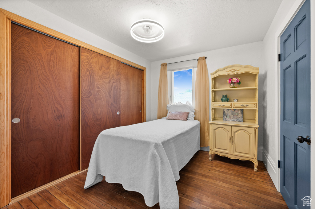 Bedroom with dark wood-type flooring and a closet