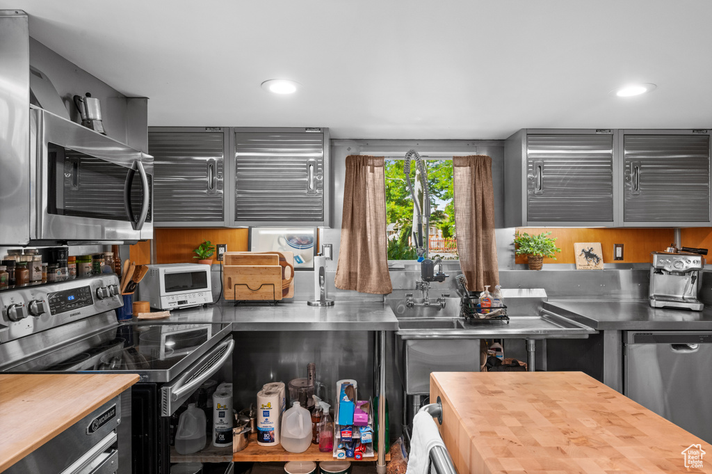 Kitchen with stainless steel countertops, stainless steel appliances, and recessed lighting