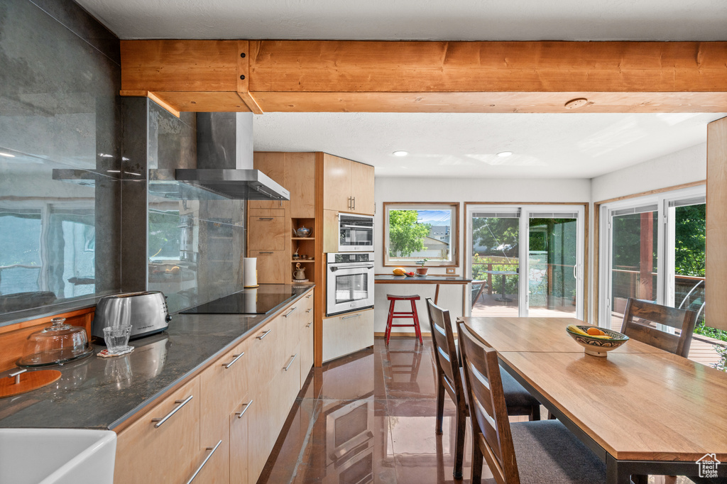 Kitchen with wall chimney exhaust hood, black electric cooktop, recessed lighting, modern cabinets, and dark stone counters