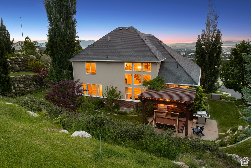 Back of property with a patio area, stucco siding, and a shingled roof
