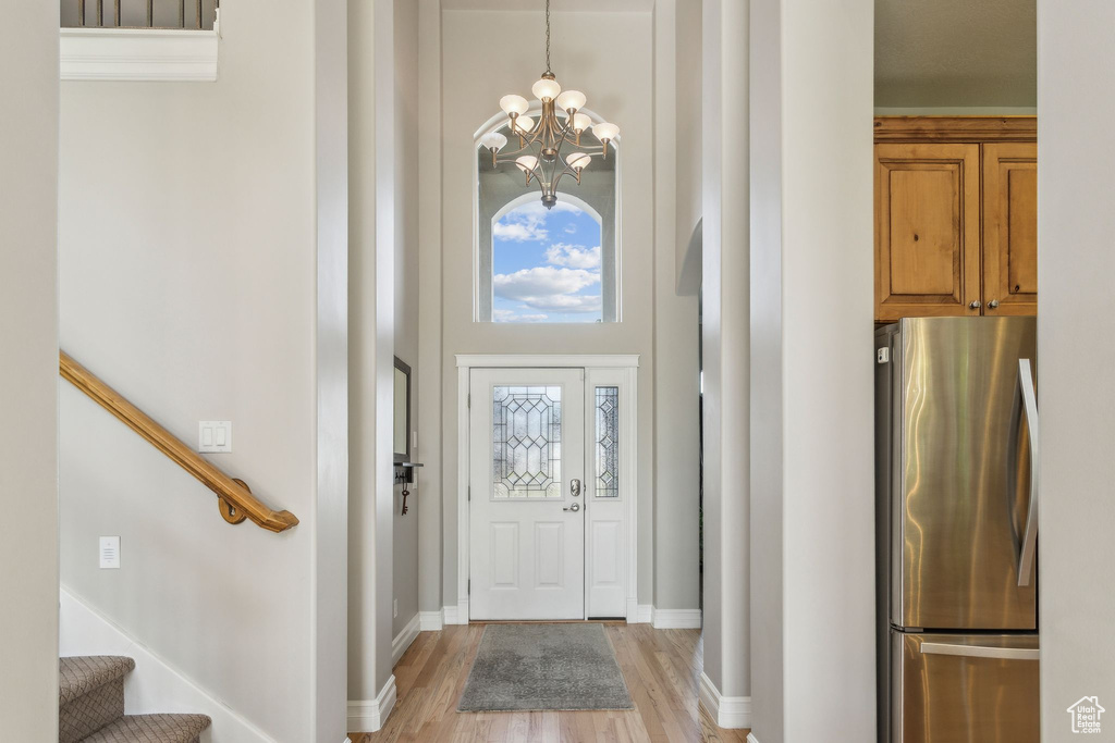 Foyer with a chandelier, a high ceiling, stairs, light wood finished floors, and baseboards