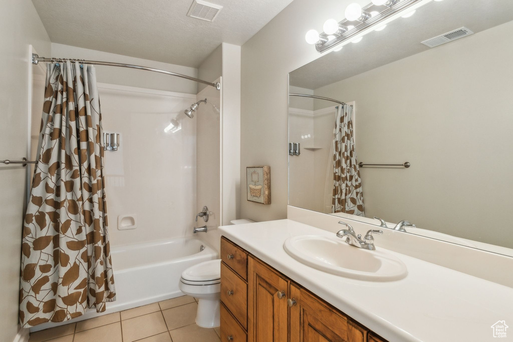 Bathroom featuring shower / bathtub combination with curtain, vanity, tile patterned flooring, and toilet