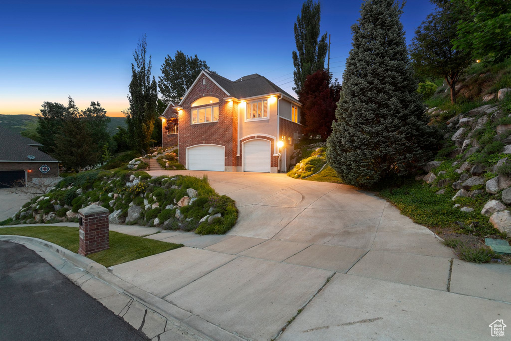 Traditional-style house with an attached garage, concrete driveway, and brick siding