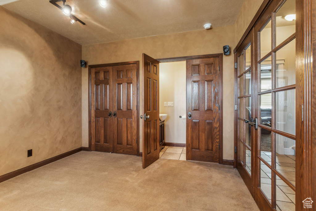 Foyer entrance with carpet, baseboards, french doors, and a textured wall