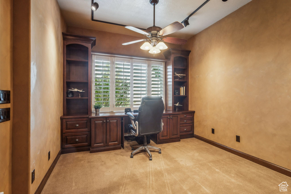 Office area featuring a ceiling fan, light colored carpet, and baseboards