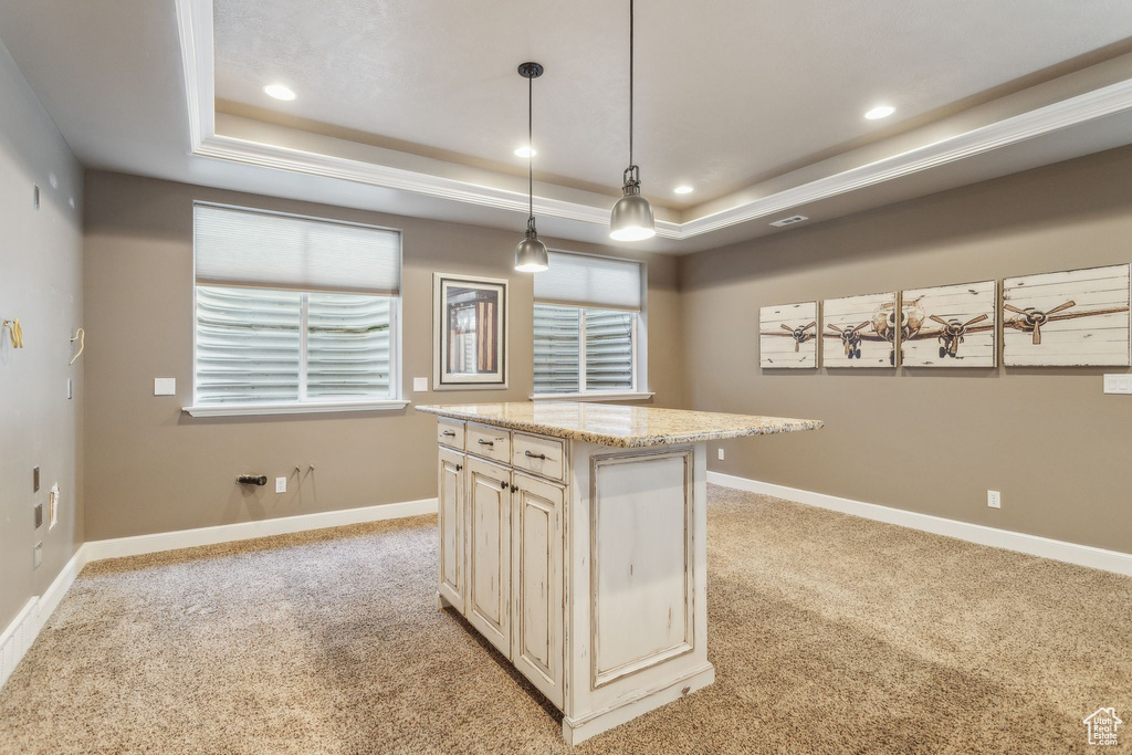 Kitchen with a raised ceiling, light colored carpet, recessed lighting, baseboards, and cream cabinets