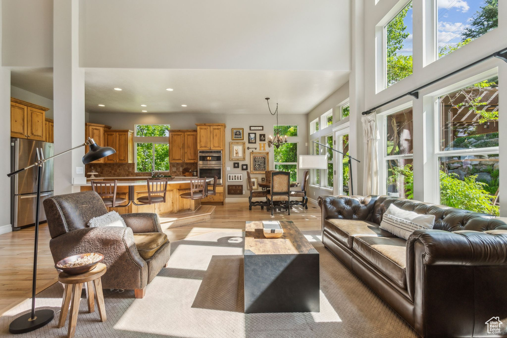 Living room featuring plenty of natural light, a towering ceiling, light wood finished floors, recessed lighting, and baseboards