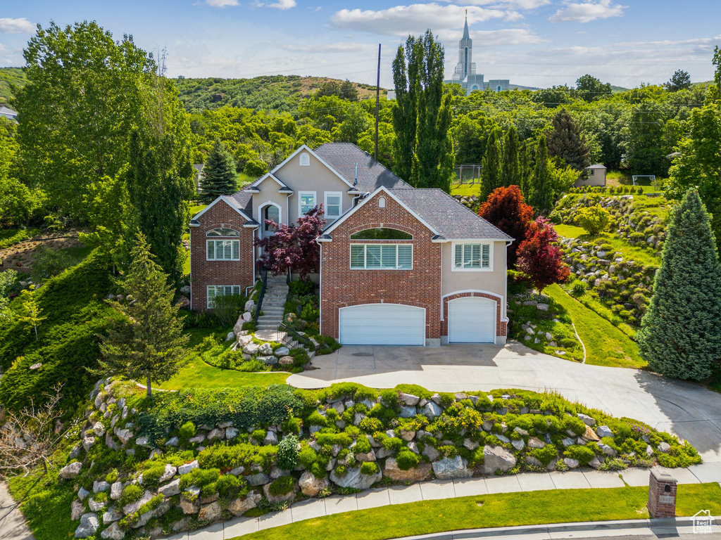 Traditional home with concrete driveway, a garage, brick siding, and stairs