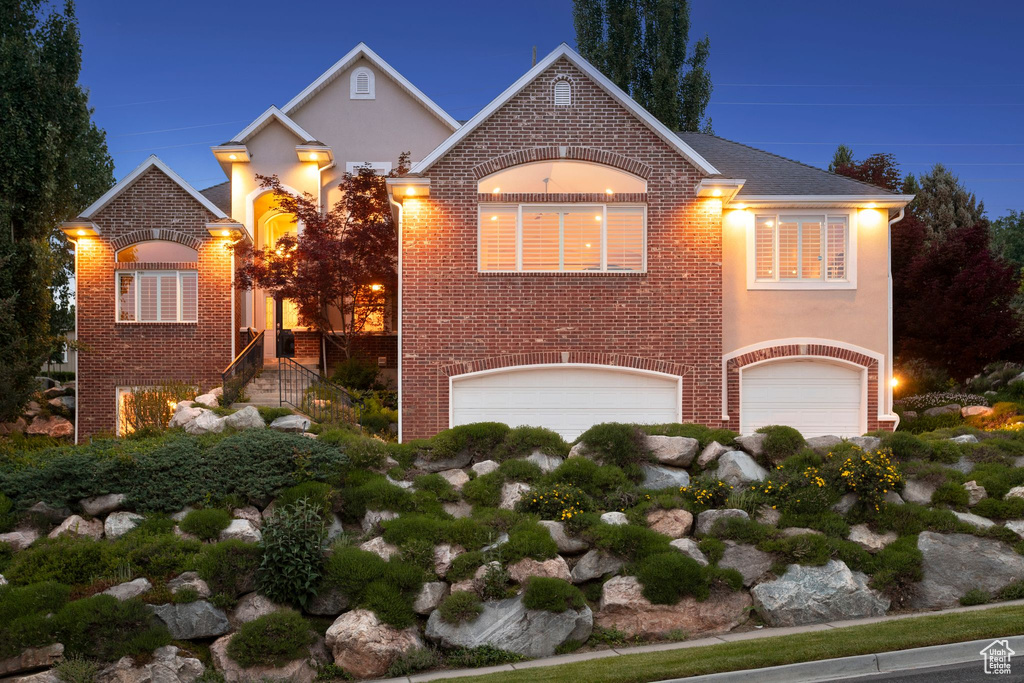 View of front facade featuring an attached garage, stucco siding, and brick siding