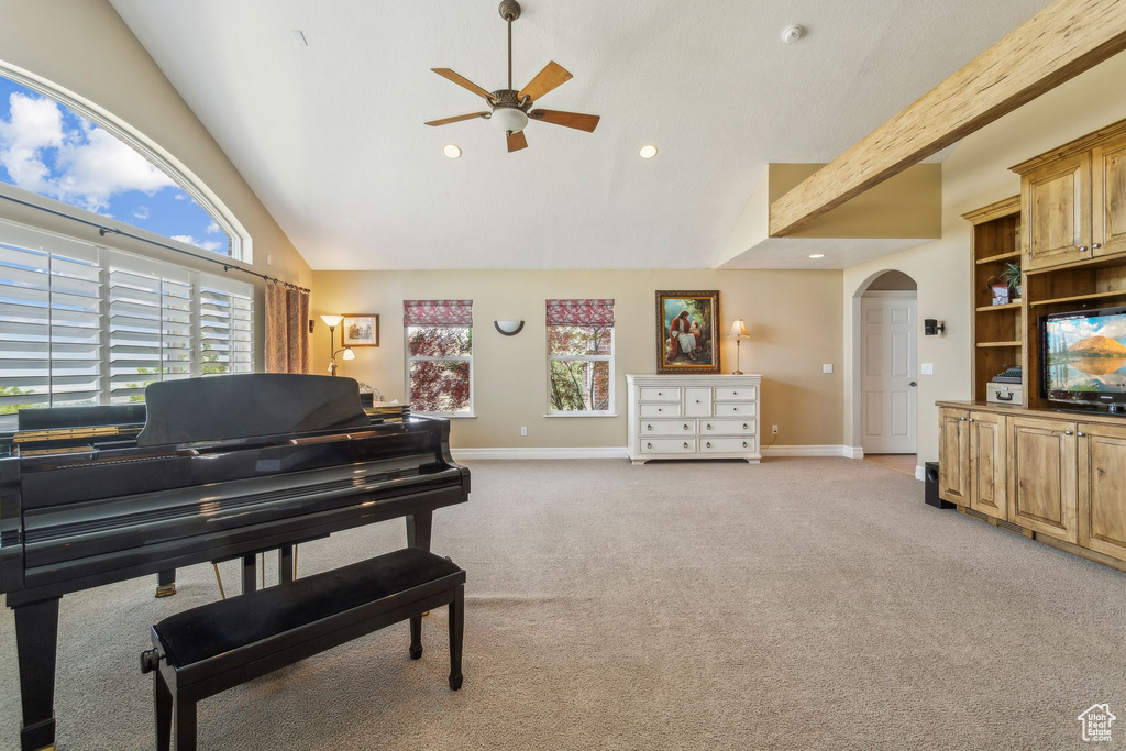 Living area featuring arched walkways, a ceiling fan, light carpet, baseboards, and high vaulted ceiling
