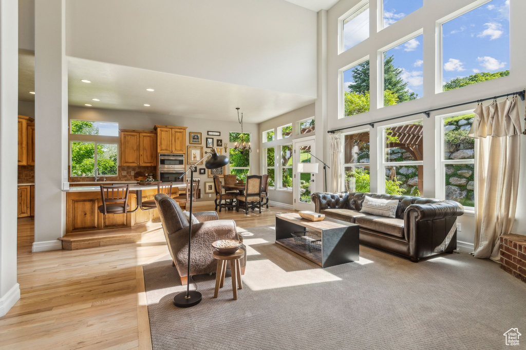 Living area with a high ceiling, light wood-style floors, recessed lighting, and baseboards
