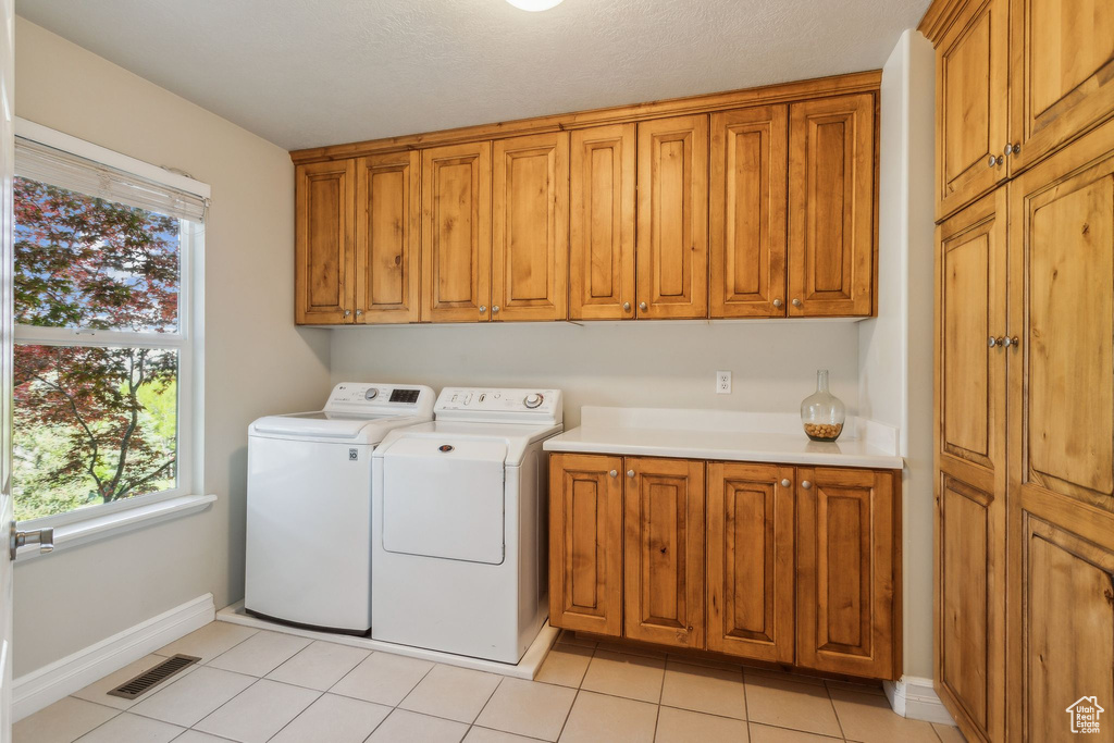 Laundry room with cabinet space, separate washer and dryer, baseboards, and healthy amount of natural light