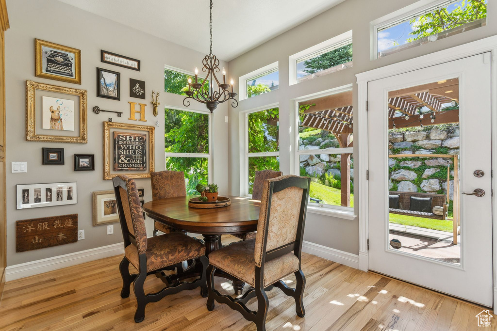 Dining space featuring baseboards, a chandelier, and light wood-style floors