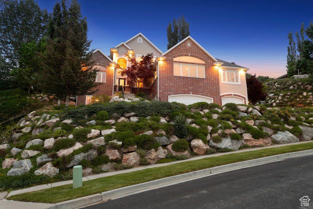 View of front of house with an attached garage, brick siding, and stairway