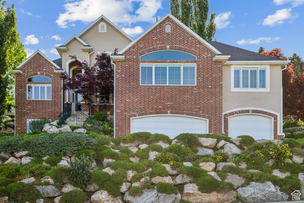 Traditional-style house with a garage, brick siding, and stucco siding