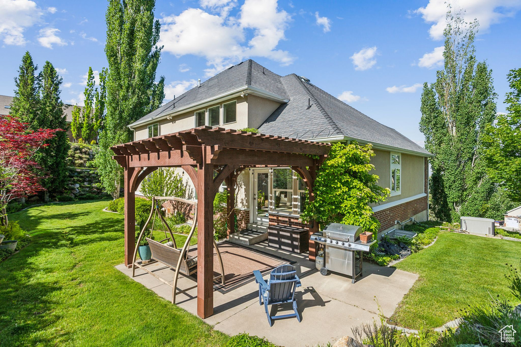 Rear view of property with a pergola, a patio area, a yard, and brick siding