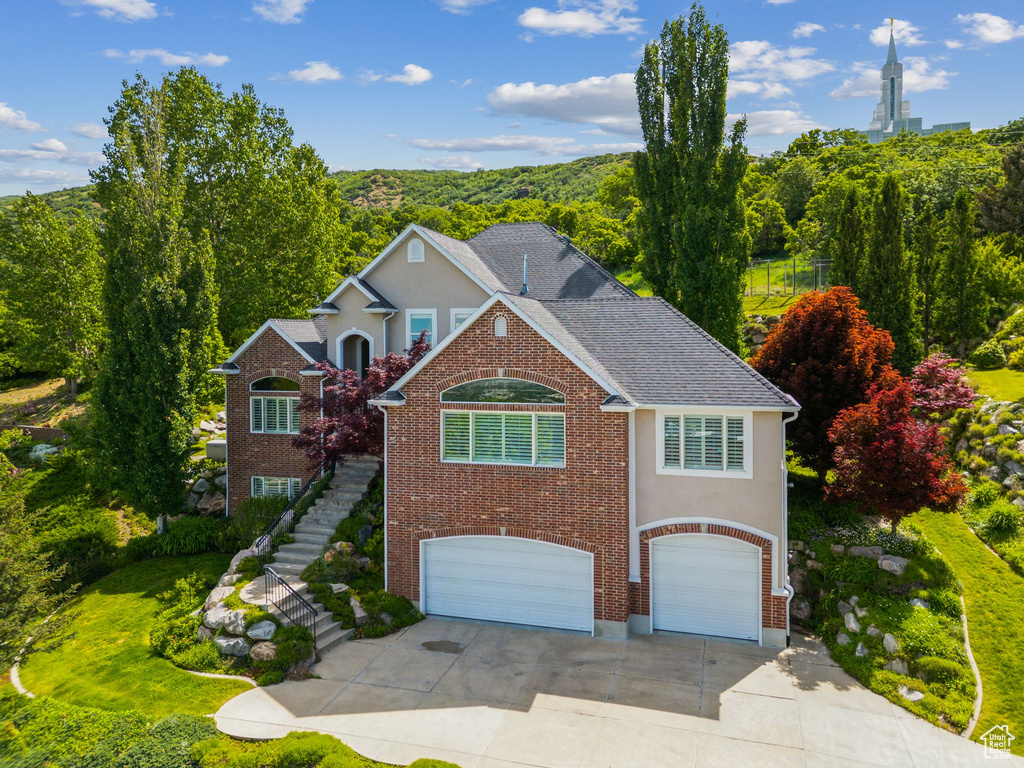 Traditional-style home featuring an attached garage, stairs, concrete driveway, and stucco siding