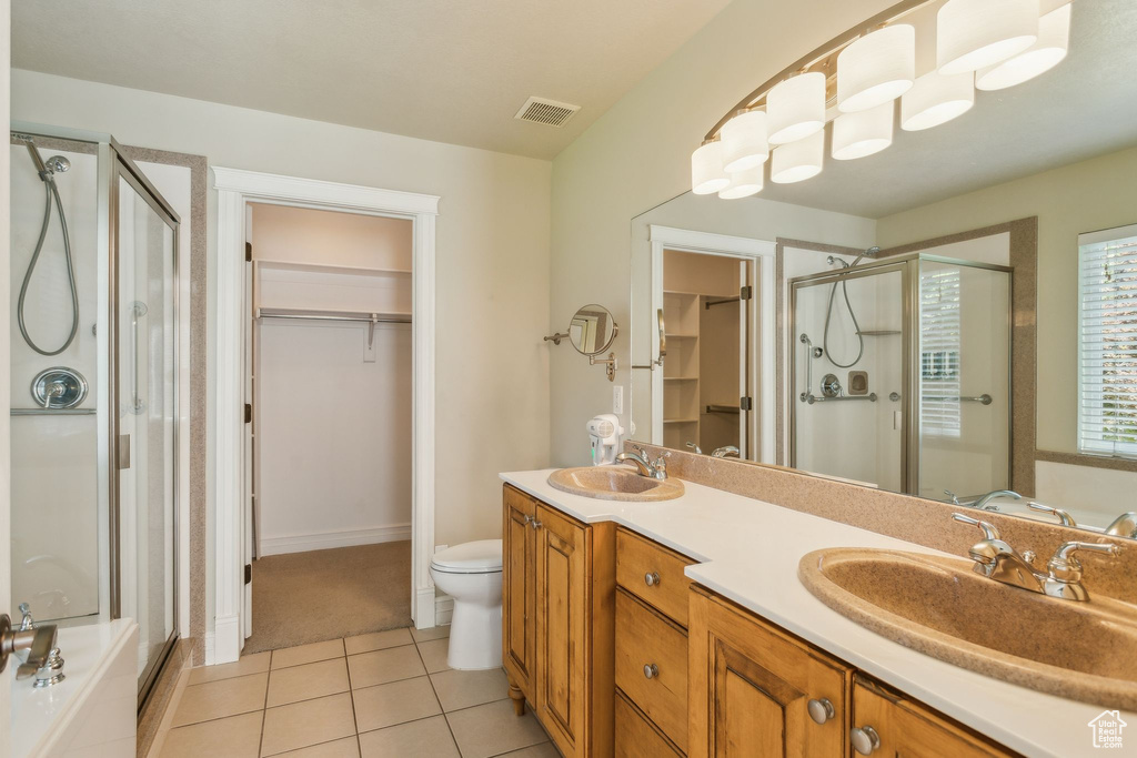 Full bathroom with a stall shower, a spacious closet, double vanity, tile patterned floors, and toilet