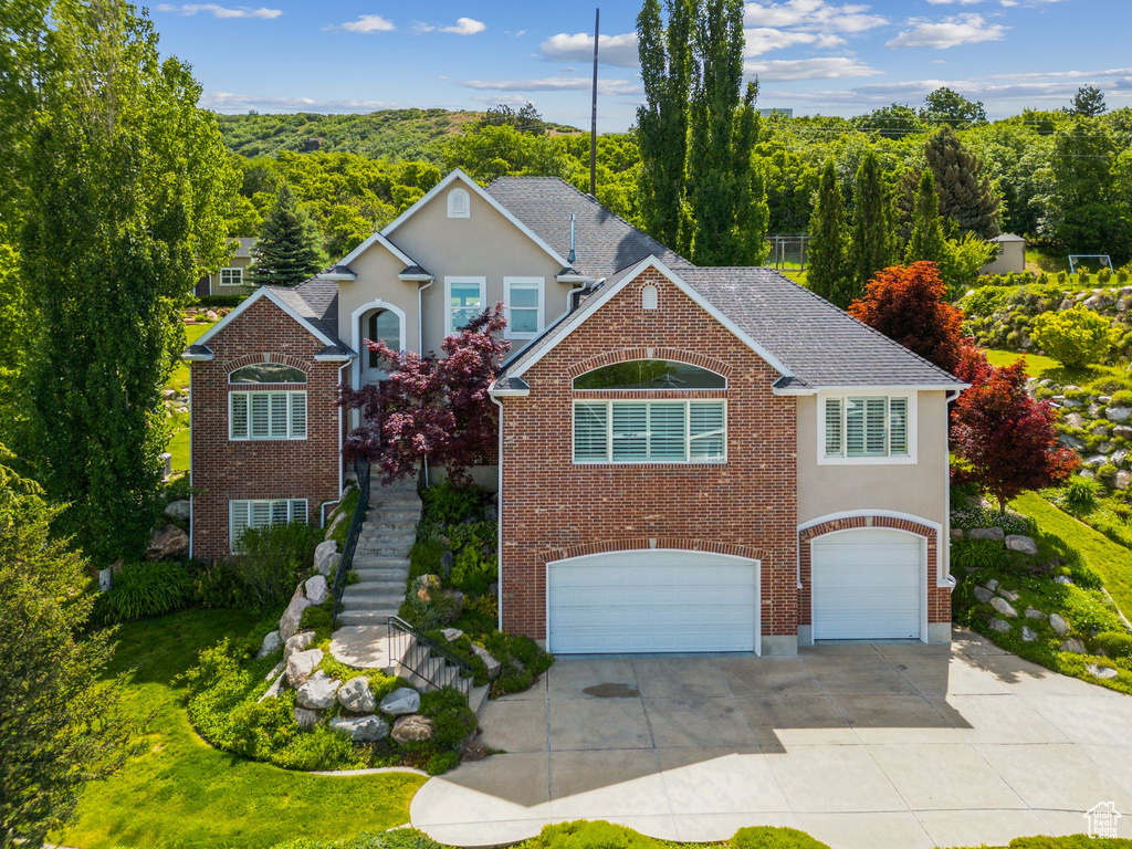 Traditional home with an attached garage, concrete driveway, stairway, and brick siding
