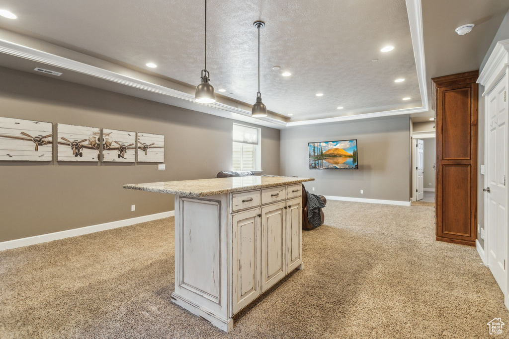 Kitchen featuring light colored carpet, recessed lighting, a raised ceiling, baseboards, and a kitchen island