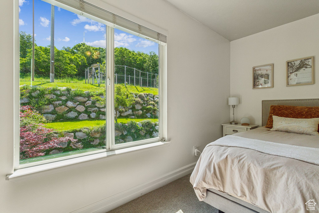 Carpeted bedroom with baseboards and view of scattered trees
