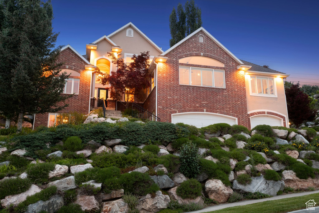 Traditional-style house featuring an attached garage, brick siding, and stucco siding