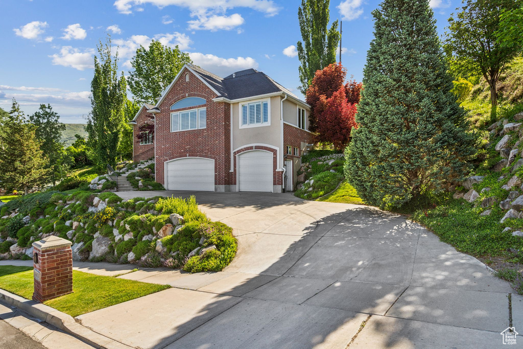View of front of property with concrete driveway, an attached garage, and brick siding