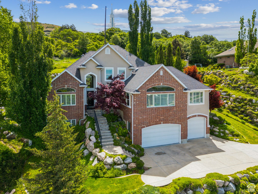 Traditional-style home featuring a garage, driveway, brick siding, and stucco siding