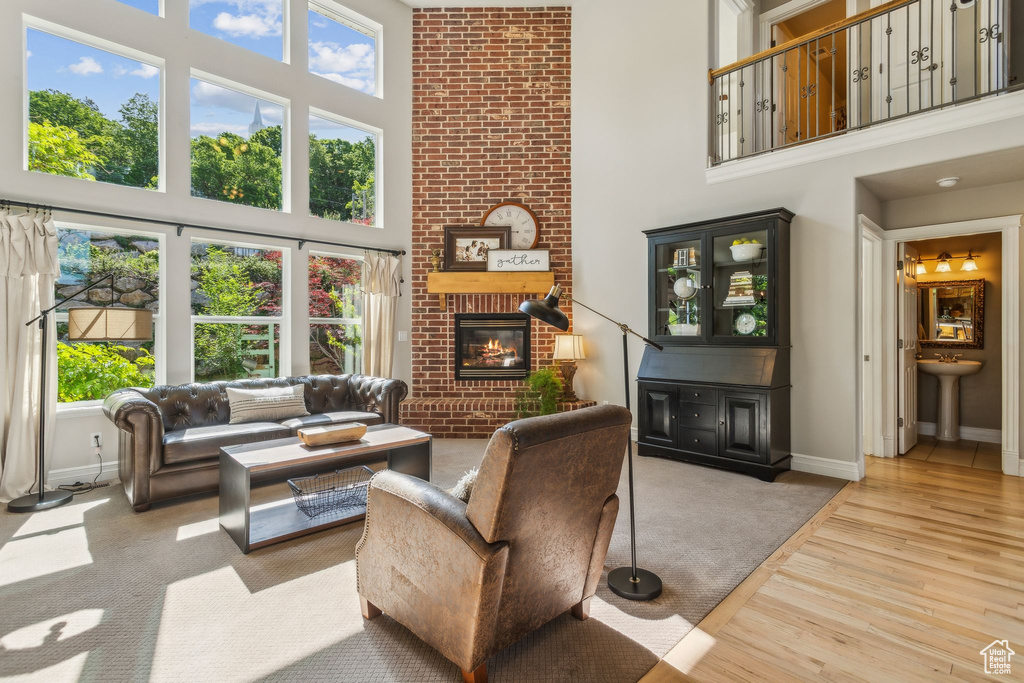 Living area featuring a towering ceiling, a fireplace, baseboards, healthy amount of natural light, and wood finished floors