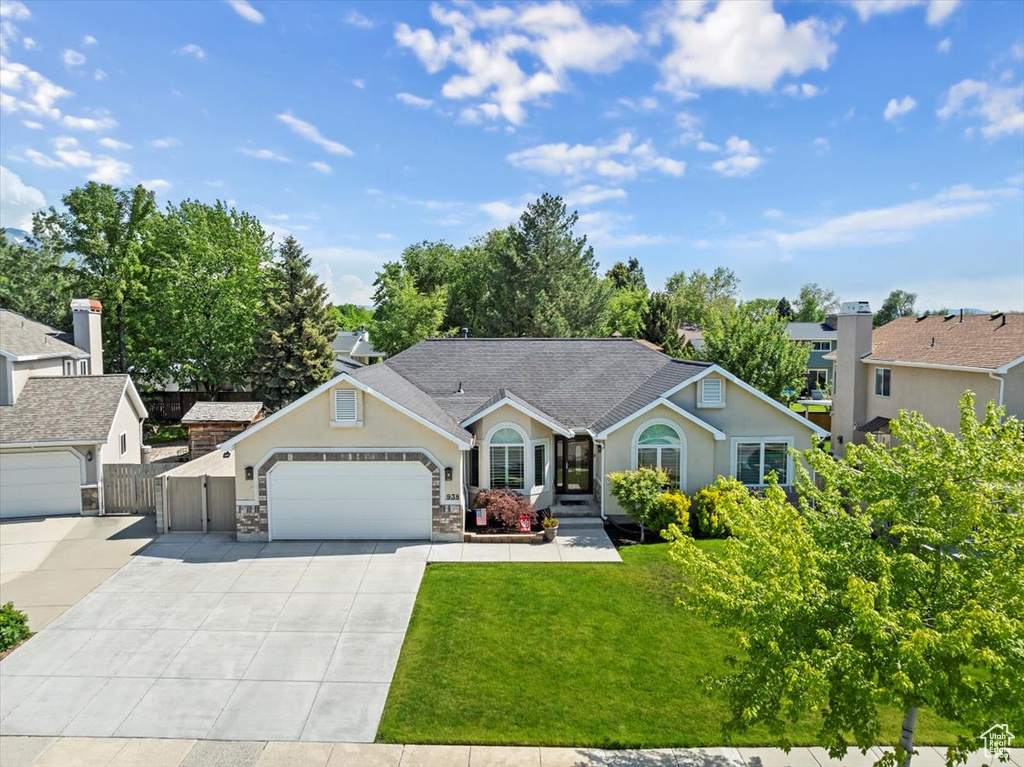 Ranch-style house with driveway, an attached garage, stucco siding, and stone siding