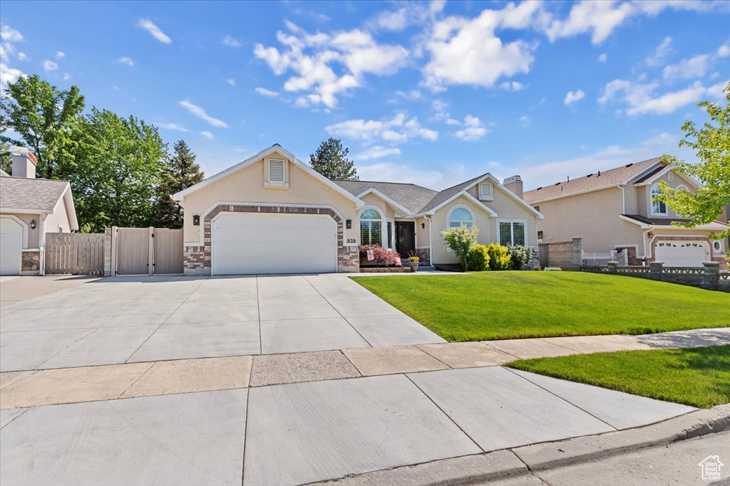 Ranch-style house with driveway, a garage, stucco siding, and a gate