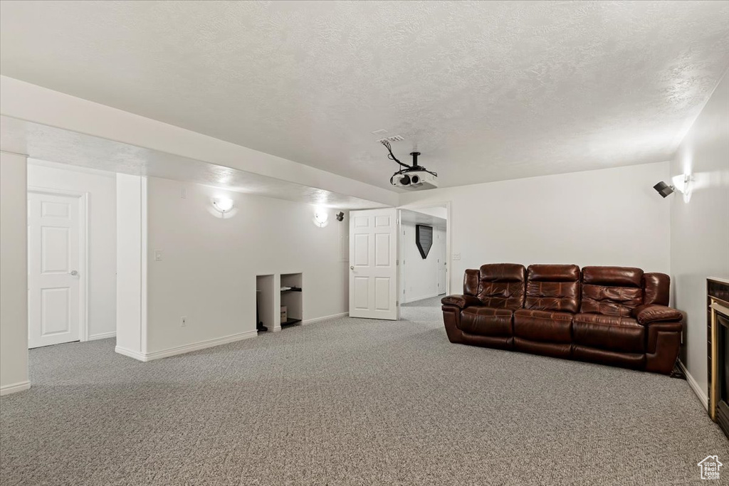 Living room featuring carpet flooring, baseboards, and a textured ceiling