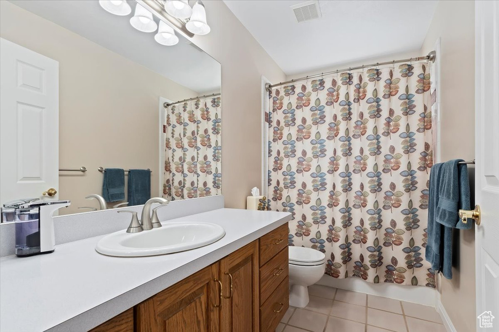 Bathroom featuring tile patterned floors, vanity, toilet, and shower / bath combo with shower curtain