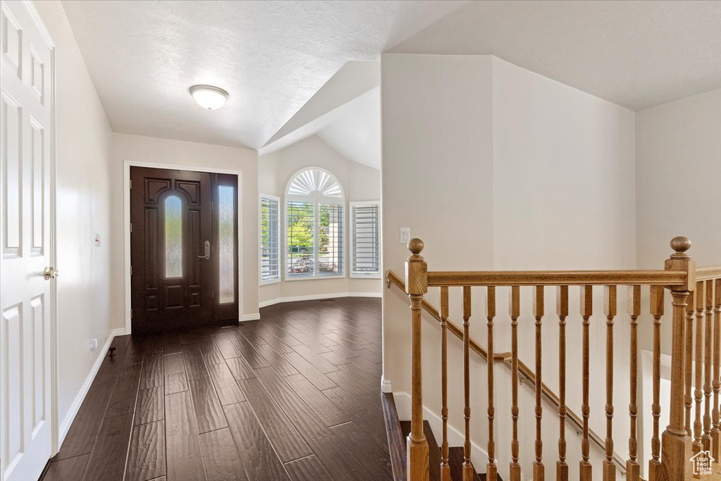 Foyer featuring dark wood-type flooring, baseboards, and vaulted ceiling