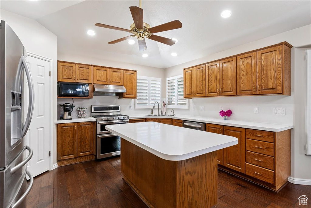 Kitchen with stainless steel appliances, under cabinet range hood, a sink, brown cabinetry, and recessed lighting