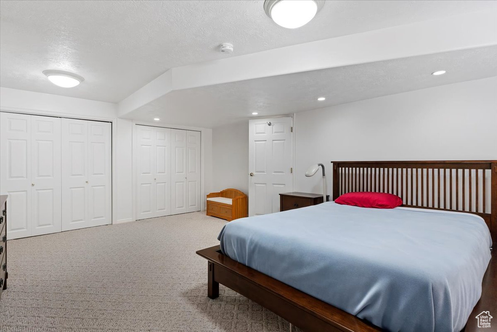 Bedroom with multiple closets, carpet, recessed lighting, and a textured ceiling