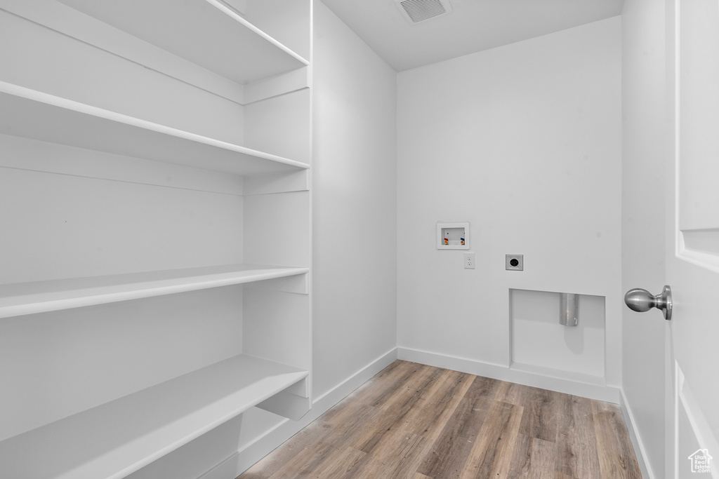 Laundry area with electric dryer hookup, washer hookup, wood finished floors, and baseboards