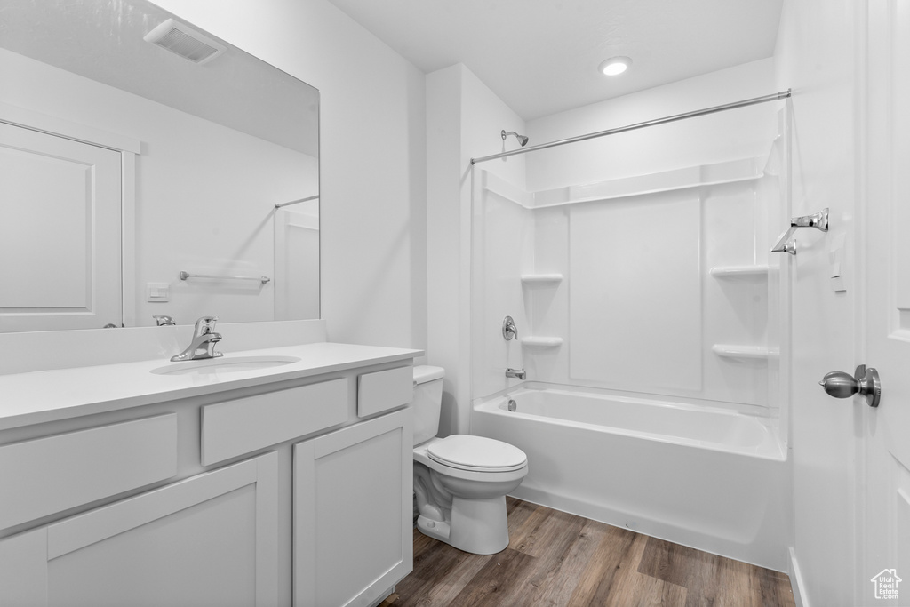 Full bathroom with washtub / shower combination, toilet, vanity, and wood finished floors