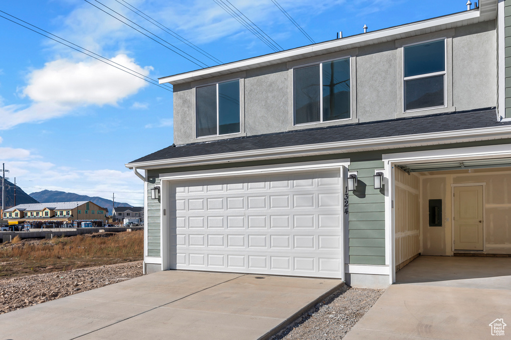 Garage featuring a mountain view, driveway, and electric panel