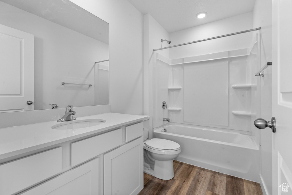 Full bath with toilet, vanity, shower / washtub combination, wood finished floors, and recessed lighting