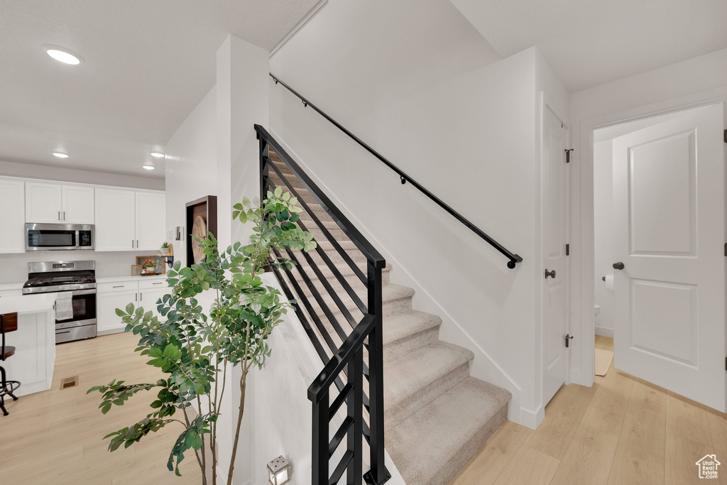 Staircase featuring wood finished floors and recessed lighting