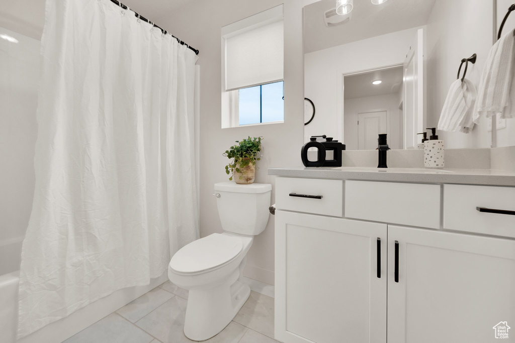 Full bathroom with tile patterned floors, toilet, vanity, shower / tub combo, and baseboards