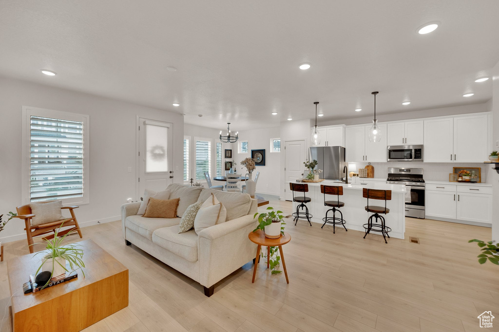 Living area featuring recessed lighting, a chandelier, light wood finished floors, and baseboards