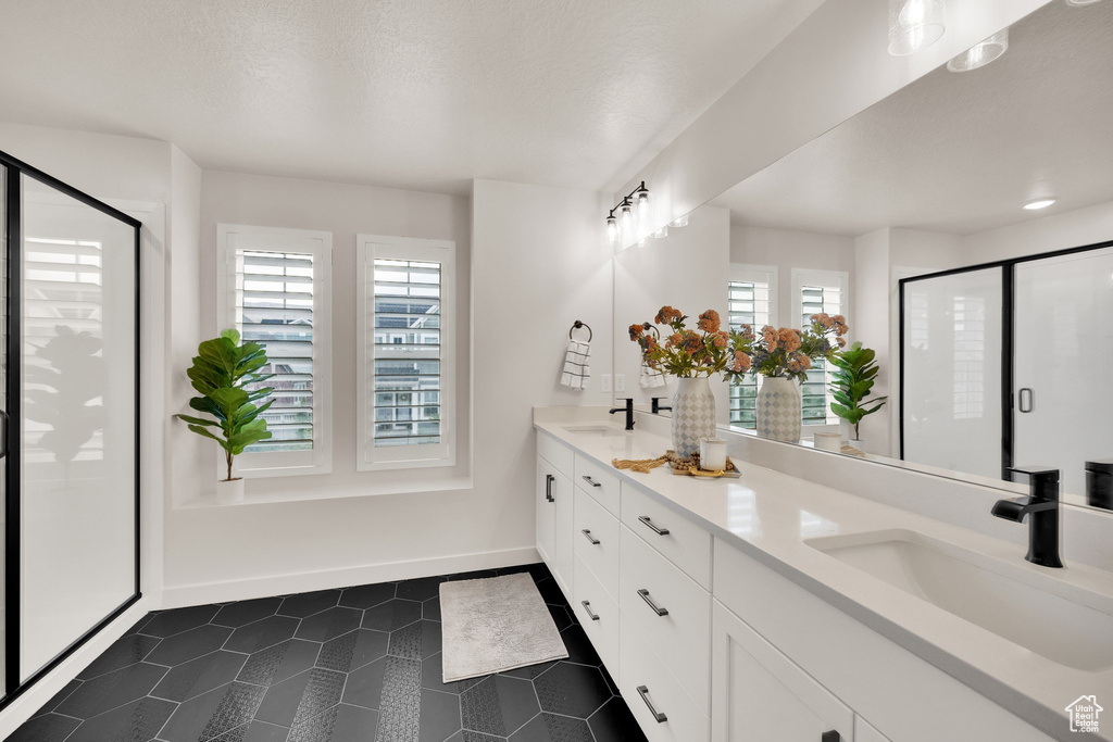 Full bathroom with tile patterned floors, double vanity, plenty of natural light, and a shower stall