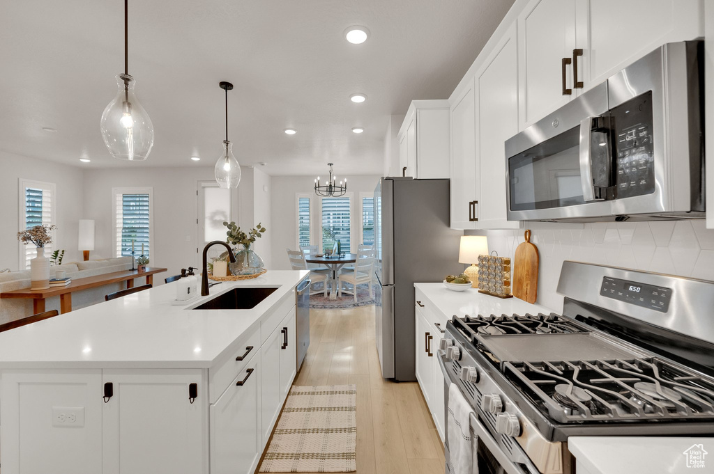 Kitchen with stainless steel appliances, a sink, recessed lighting, white cabinets, and a chandelier