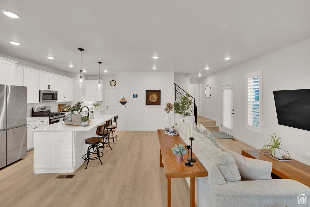 Living area featuring recessed lighting, stairway, light wood-style flooring, and baseboards