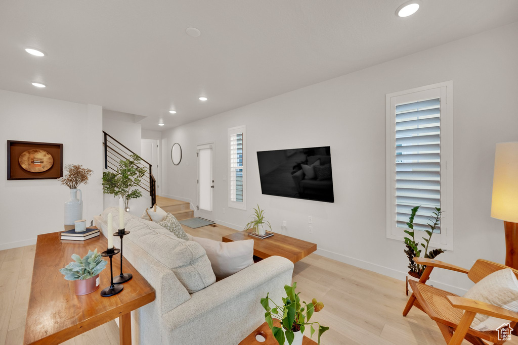 Living room with recessed lighting, light wood finished floors, stairway, and baseboards