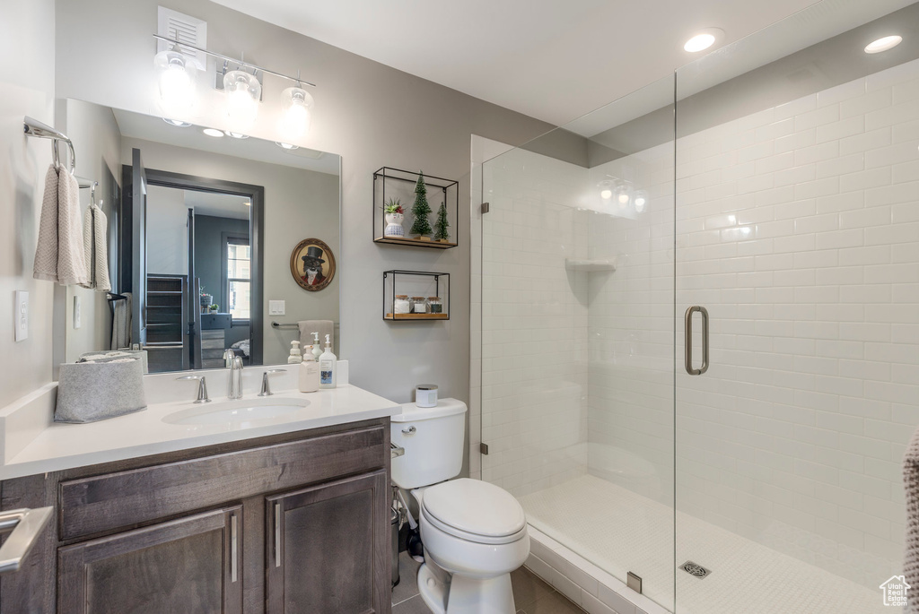 Bathroom with a stall shower, vanity, toilet, tile patterned flooring, and recessed lighting
