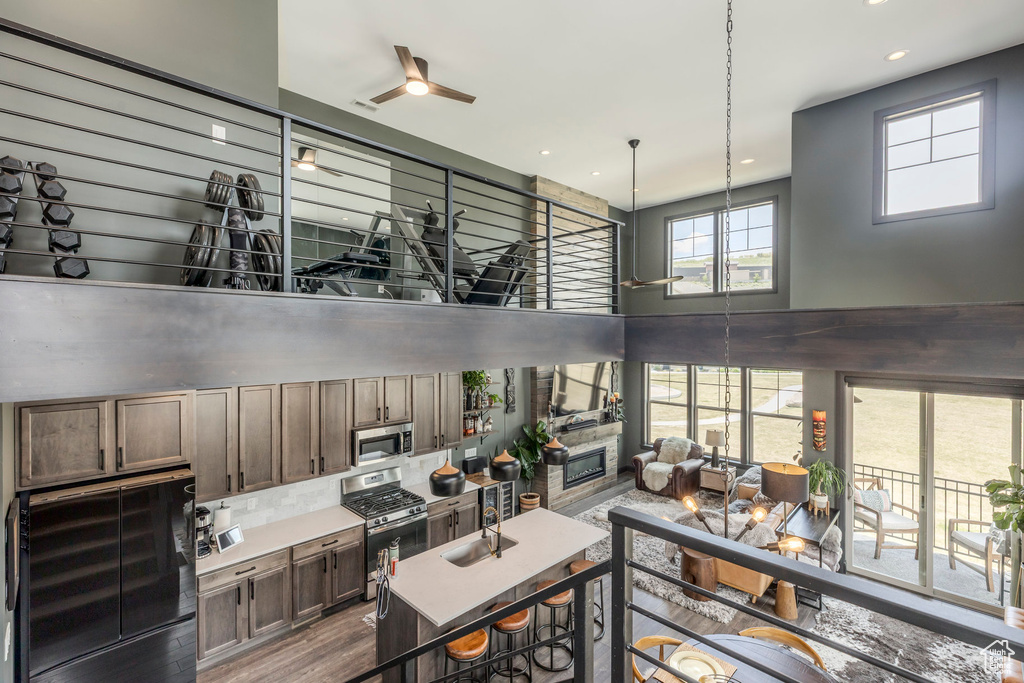 Kitchen featuring appliances with stainless steel finishes, a sink, ceiling fan, a towering ceiling, and wood finished floors
