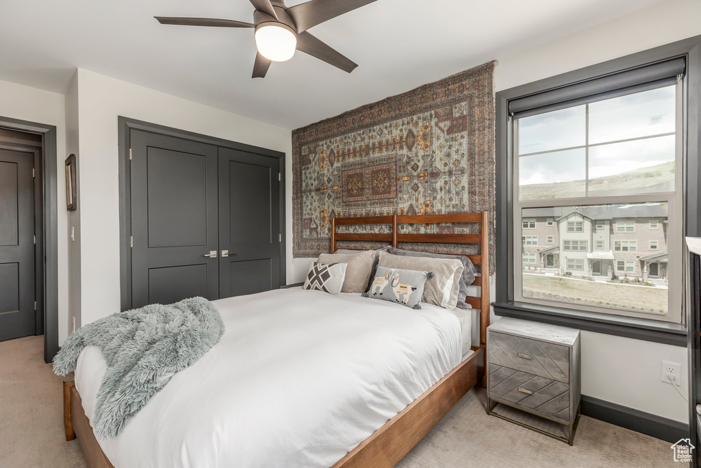 Bedroom featuring light carpet, a closet, and a ceiling fan